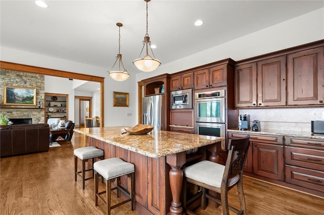 49 Waterside Dr SE, Cartersville, GA 30121 - kitchen featuring appliances with stainless steel finishes, a breakfast bar area, a kitchen island, recessed lighting, and light stone countertops
