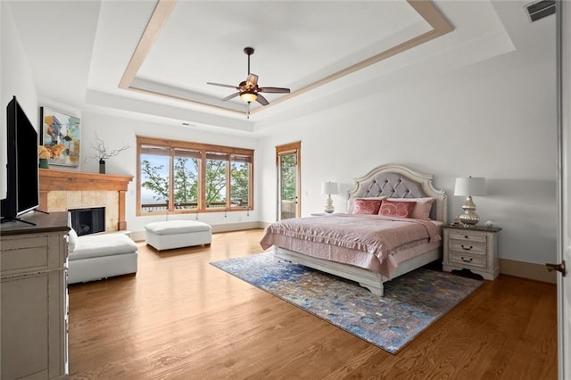 49 Waterside Dr SE, Cartersville, GA 30121 - bedroom featuring a raised ceiling, wood finished floors, a fireplace, access to exterior, and a ceiling fan