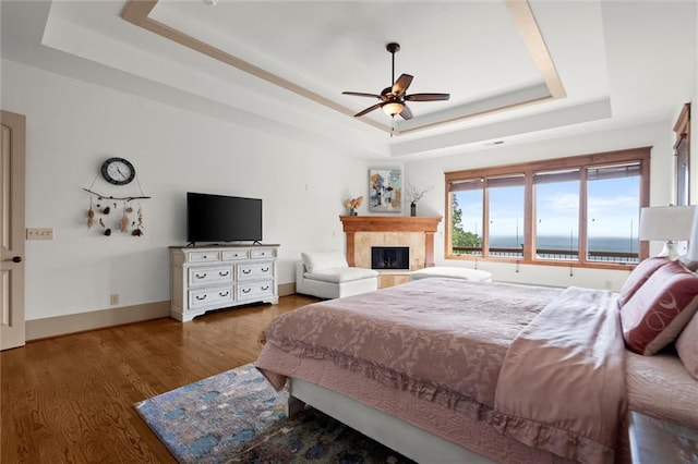 49 Waterside Dr SE, Cartersville, GA 30121 - bedroom featuring a tray ceiling, a tile fireplace, wood finished floors, and ceiling fan