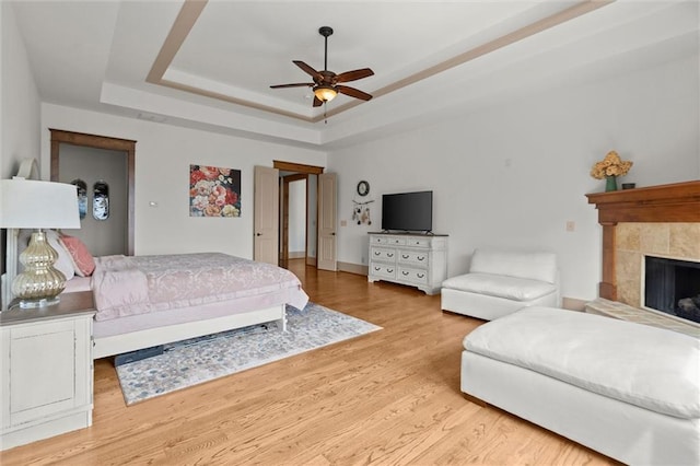 49 Waterside Dr SE, Cartersville, GA 30121 - bedroom with a tray ceiling, light wood-style floors, and a tiled fireplace