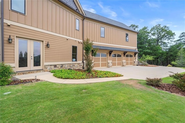 49 Waterside Dr SE, Cartersville, GA 30121 - rear view of property with board and batten siding, a garage, driveway, stone siding, and a lawn