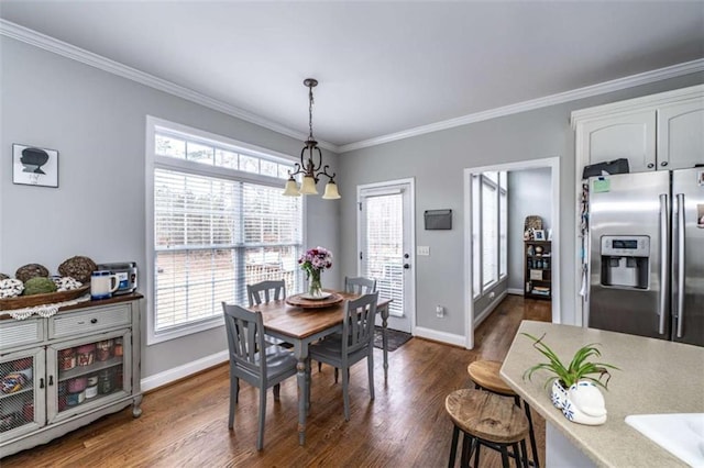 dining room with dark hardwood / wood-style floors, a healthy amount of sunlight, crown molding, and an inviting chandelier