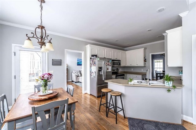 kitchen featuring dark wood-type flooring, stainless steel appliances, kitchen peninsula, a chandelier, and white cabinets