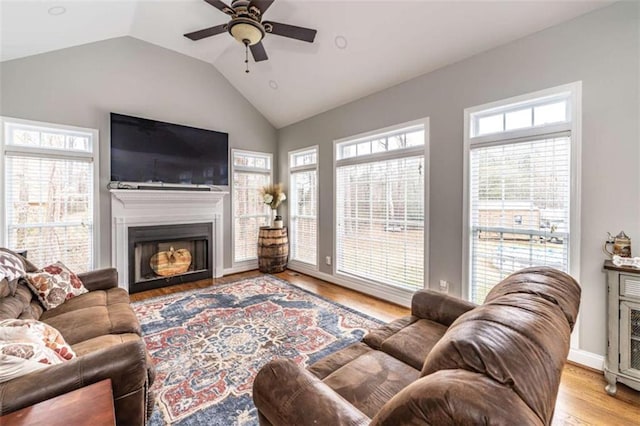 living room with a wealth of natural light, vaulted ceiling, light hardwood / wood-style flooring, and ceiling fan