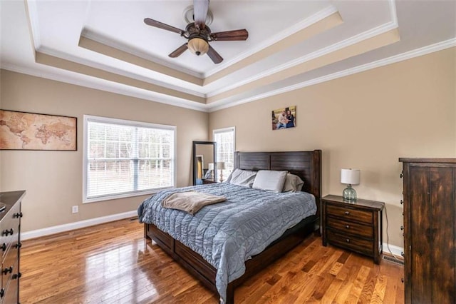 bedroom with wood-type flooring, a raised ceiling, ceiling fan, and ornamental molding