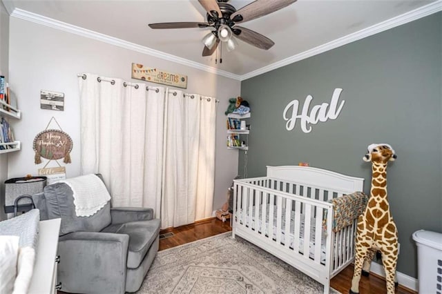 bedroom featuring crown molding, ceiling fan, hardwood / wood-style floors, and a nursery area