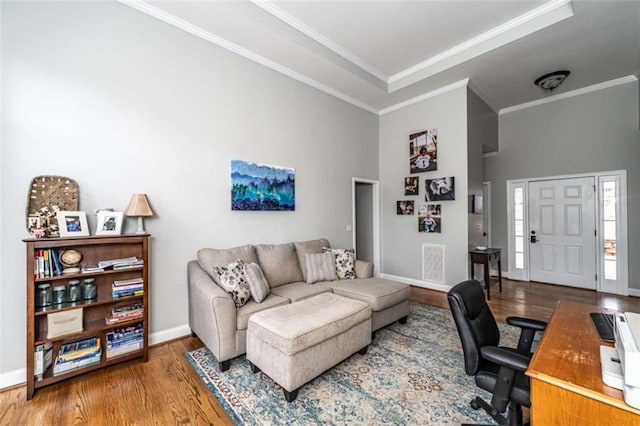 office space with crown molding, a towering ceiling, and wood-type flooring