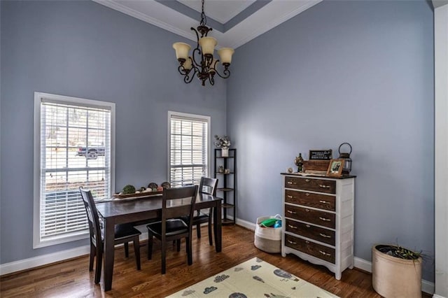 dining space featuring crown molding, a raised ceiling, dark wood-type flooring, and a chandelier