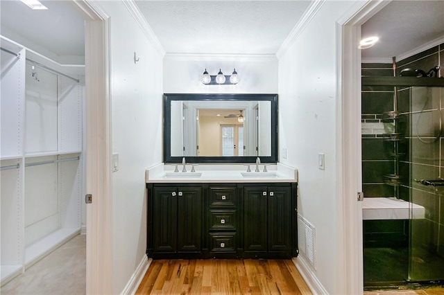 bathroom featuring vanity, hardwood / wood-style flooring, a shower with door, and crown molding