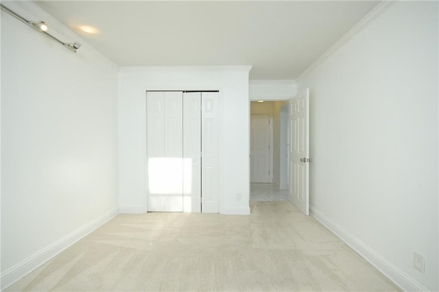 unfurnished bedroom featuring crown molding, light carpet, and a closet