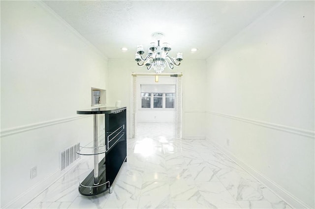 hallway with an inviting chandelier and ornamental molding