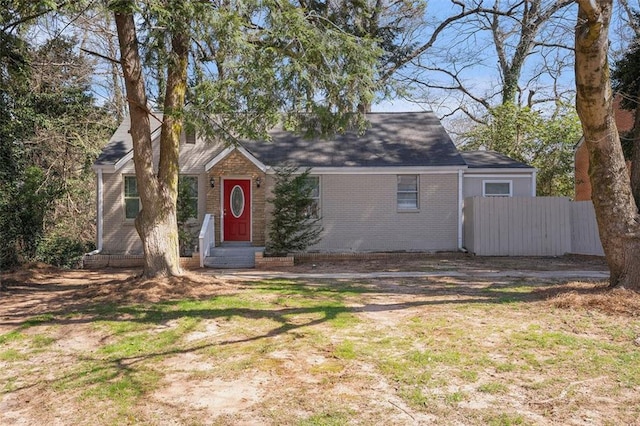 view of front of house featuring entry steps, brick siding, and fence