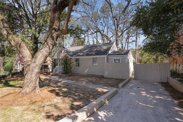 view of front of property with driveway, brick siding, and fence