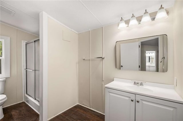 bathroom with hardwood / wood-style floors, vanity, a shower with shower door, and toilet