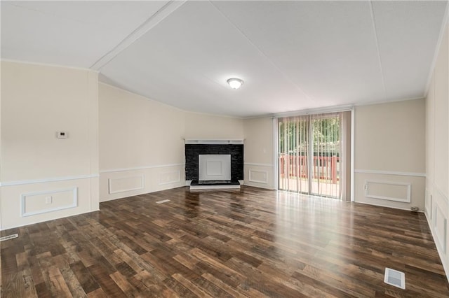 unfurnished living room featuring dark hardwood / wood-style floors, a stone fireplace, and crown molding