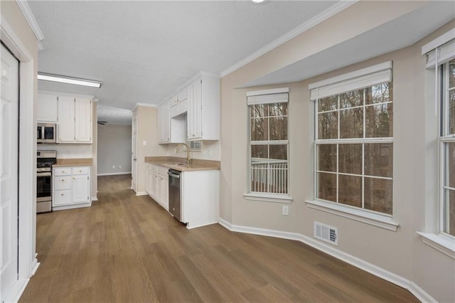 kitchen with appliances with stainless steel finishes, dark hardwood / wood-style floors, sink, and white cabinets