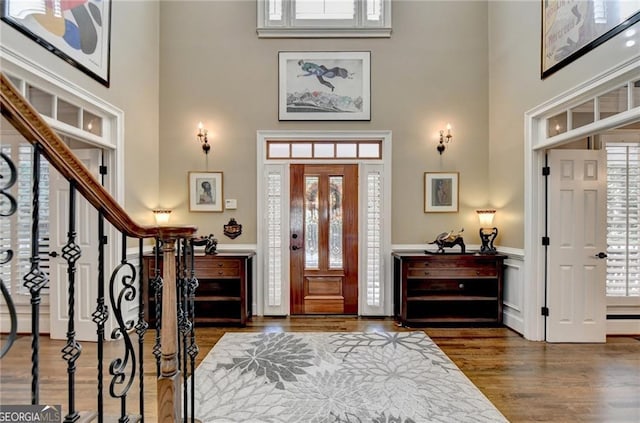 foyer featuring a wainscoted wall, a high ceiling, and wood finished floors