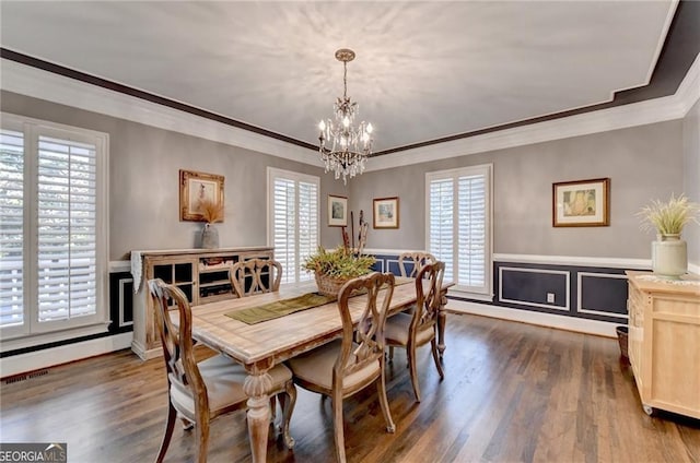 dining area featuring dark wood-style flooring, a chandelier, a healthy amount of sunlight, and crown molding