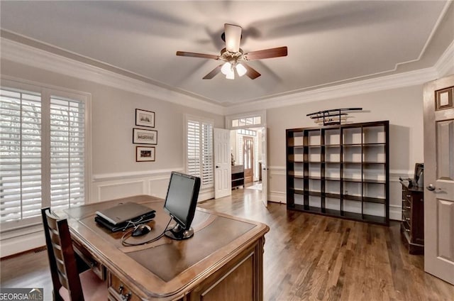 office area featuring wood finished floors, ceiling fan, crown molding, and a wainscoted wall