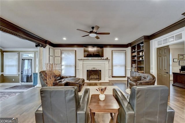 living room featuring a wealth of natural light, wood finished floors, a ceiling fan, and crown molding