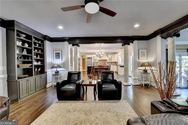 living room featuring ornate columns, crown molding, and ceiling fan with notable chandelier