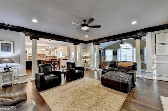 living area with decorative columns, ornamental molding, ceiling fan with notable chandelier, and a decorative wall