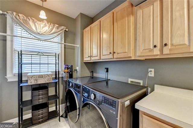 clothes washing area featuring light floors, washer and dryer, and cabinet space