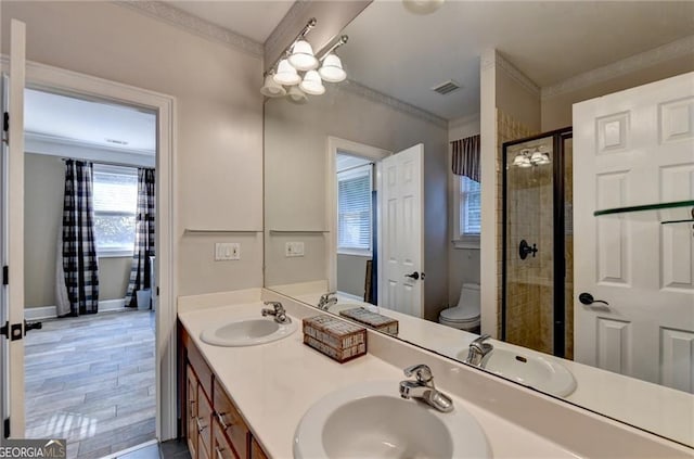 bathroom with visible vents, toilet, a shower stall, and a sink