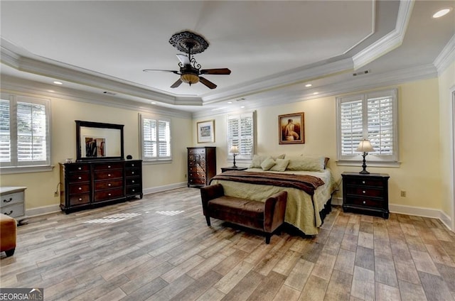 bedroom featuring a raised ceiling, light wood-type flooring, crown molding, and visible vents