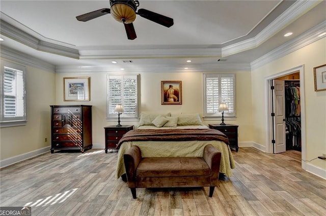 bedroom with crown molding, a raised ceiling, and light wood-type flooring