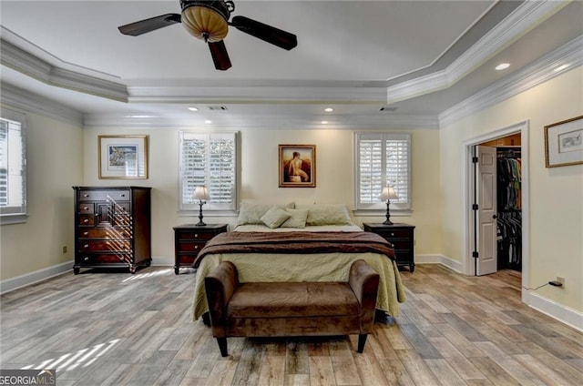 bedroom with crown molding, light wood finished floors, multiple windows, and a raised ceiling