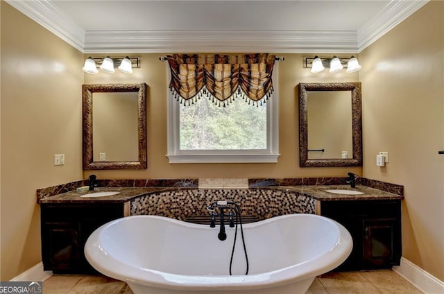bathroom featuring a freestanding tub, vanity, ornamental molding, and baseboards