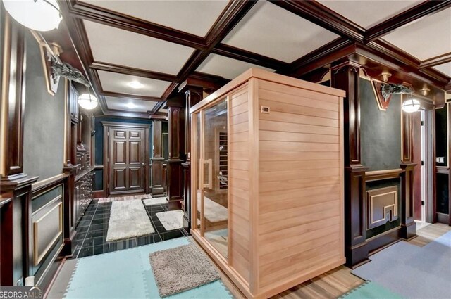 interior space featuring ornamental molding, coffered ceiling, and a decorative wall