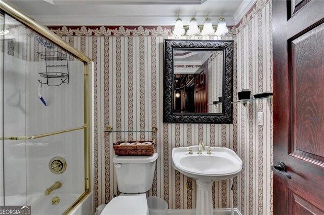 full bathroom featuring bath / shower combo with glass door, toilet, crown molding, and wallpapered walls