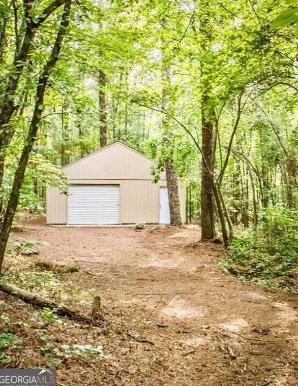 detached garage featuring a view of trees