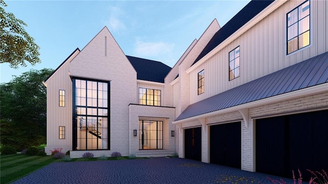 back of property featuring a garage, brick siding, board and batten siding, and aphalt driveway