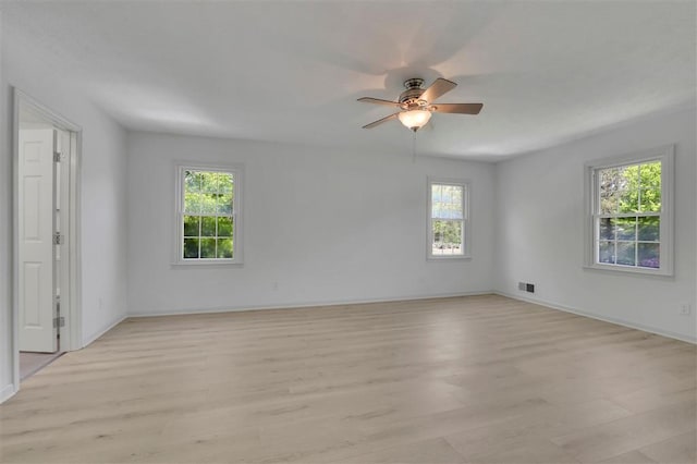 spare room with light wood-type flooring, baseboards, a ceiling fan, and visible vents