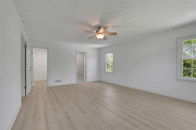 empty room featuring visible vents, a wealth of natural light, light wood-type flooring, and a ceiling fan