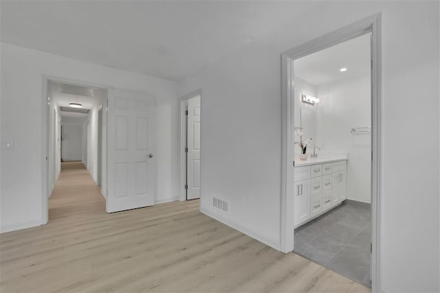 interior space featuring light wood-type flooring, attic access, baseboards, and visible vents