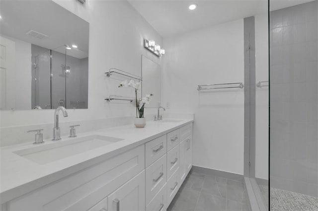 full bath featuring a sink, visible vents, tiled shower, and double vanity