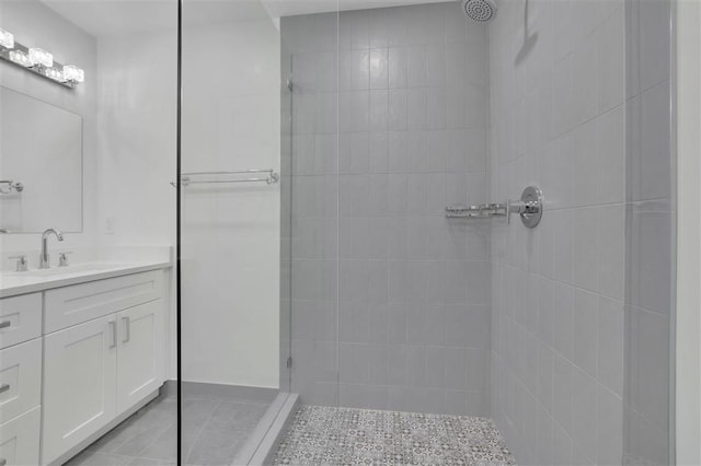 full bath with tiled shower, vanity, and tile patterned flooring