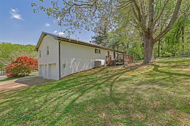 view of side of property with an attached garage, a yard, driveway, and central AC unit