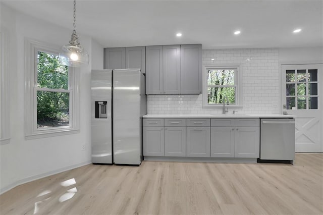 kitchen with tasteful backsplash, gray cabinets, a sink, and appliances with stainless steel finishes