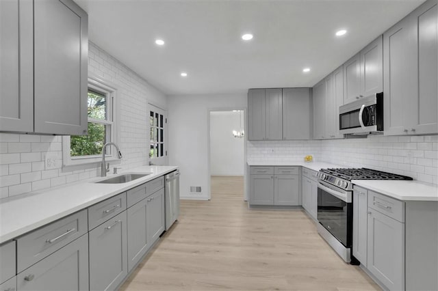 kitchen with a sink, appliances with stainless steel finishes, light wood-style floors, recessed lighting, and gray cabinets