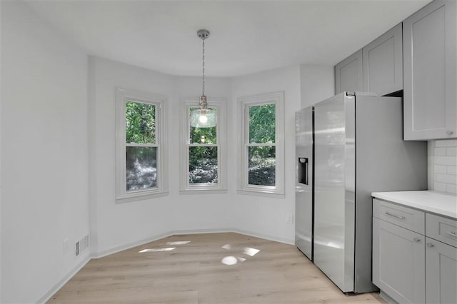kitchen with visible vents, baseboards, stainless steel fridge, backsplash, and light wood-style flooring