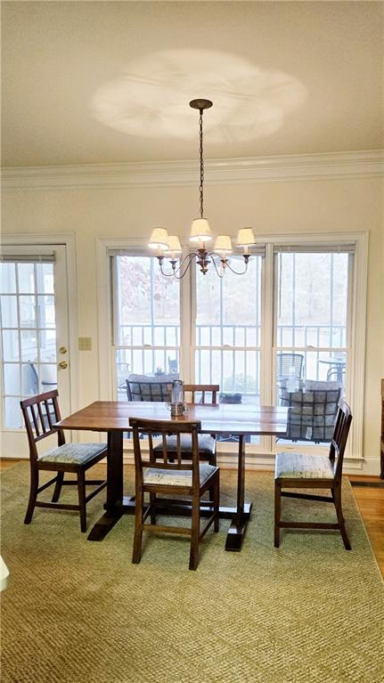 dining room featuring a healthy amount of sunlight, crown molding, and a chandelier