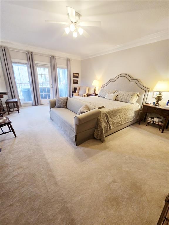 carpeted bedroom with ornamental molding and ceiling fan