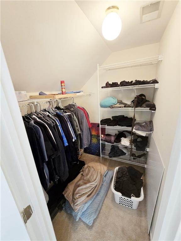 walk in closet with vaulted ceiling and carpet floors