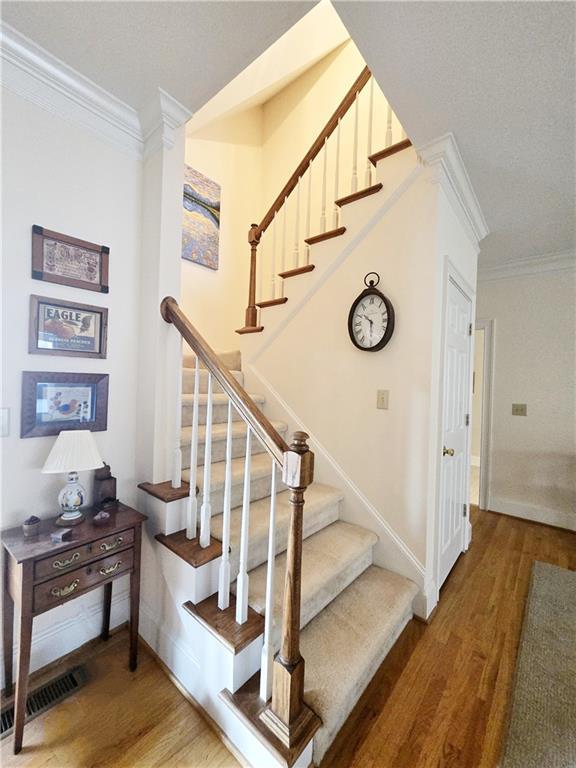 stairs with crown molding and hardwood / wood-style floors