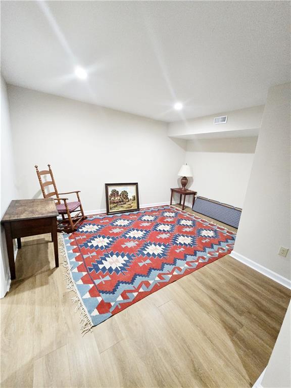 sitting room with wood finished floors, visible vents, and baseboards